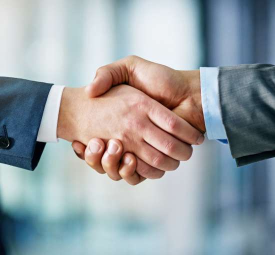 Close-up of two business professionals shaking hands, symbolizing partnership, agreement, and collaboration.